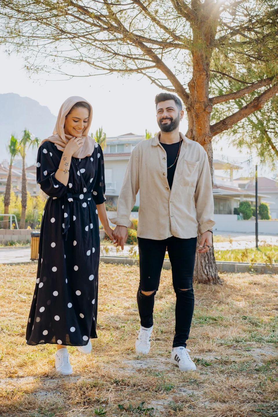 Deux adultes marchent ensemble sous les arbres.