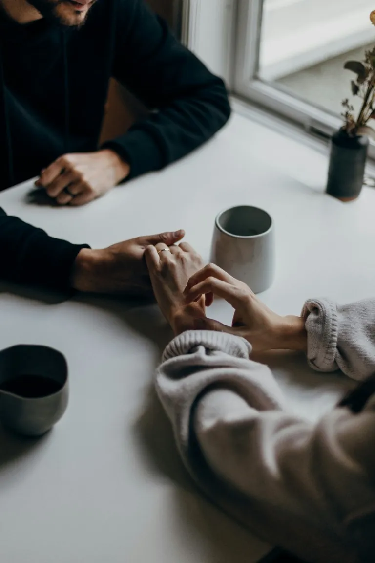 Deux adultes se tiennent la main de part et d’autre d’une table.