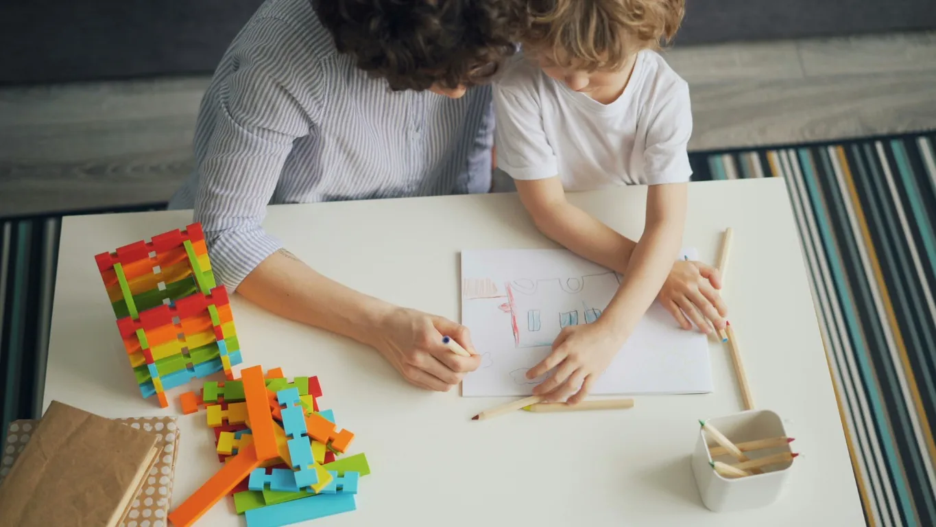 Un adulte et un enfant dessinent ensemble à une table.