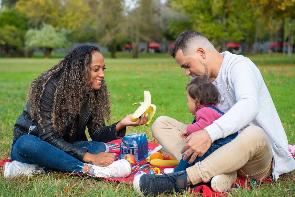 Deux parents et leur enfant partagent un moment dans un parc.